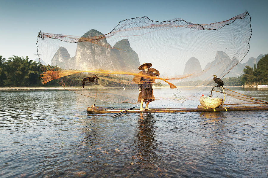 Fisherman On Bamboo Boat Throwing The Photograph by Matteo Colombo