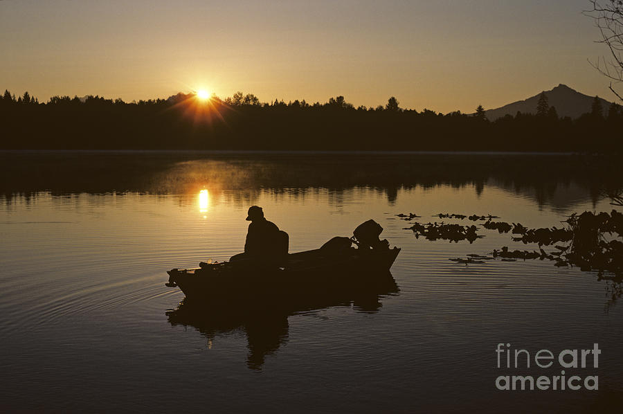 Fisherman on small lake silhouetted Photograph by Jim Corwin