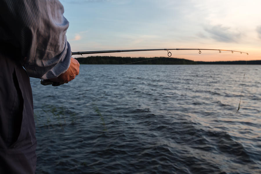 Fishing by the lake at sunset Photograph by Sami Hurmerinta