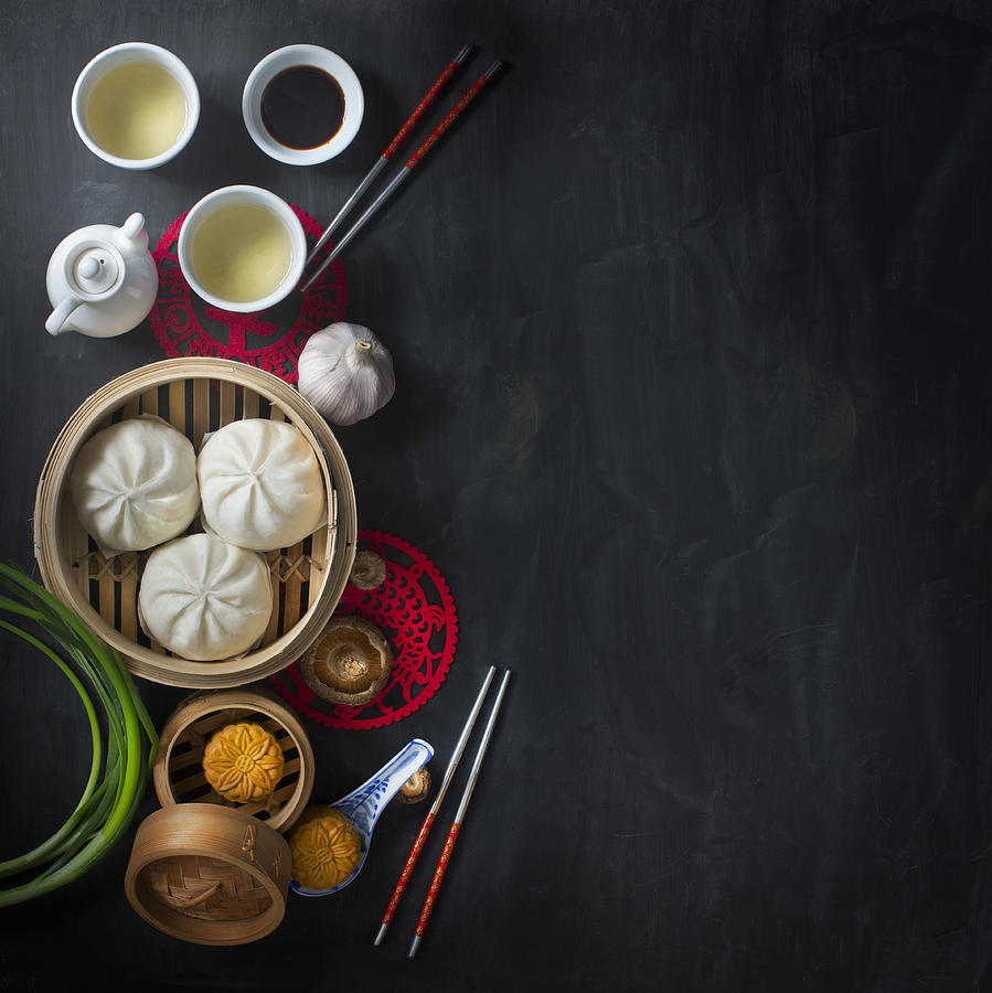 Flat lay Chinese food and drink on moody rustic table top. Photograph by Twomeows