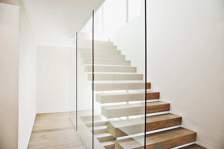 Floating staircase and glass walls in modern house Photograph by Martin Barraud