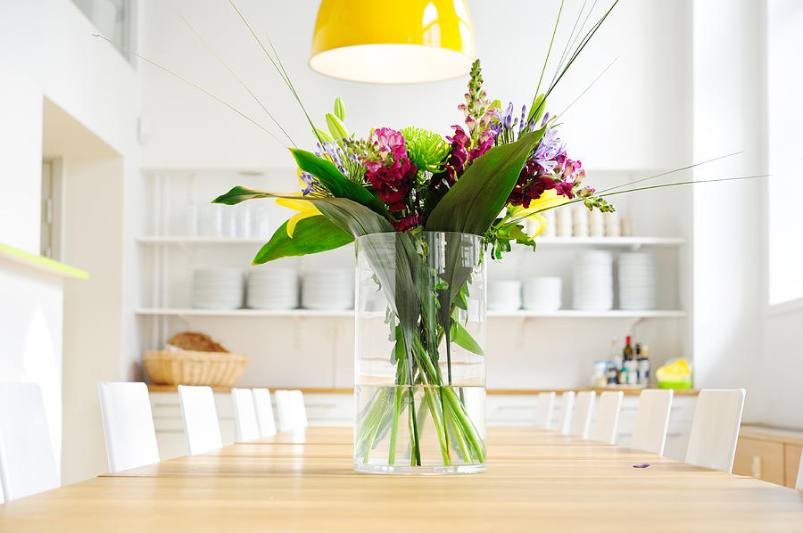 Flowers on table in bright large kitchen Photograph by Olaser