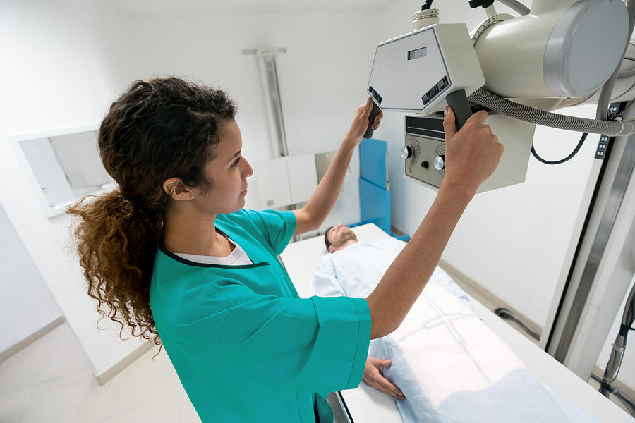 Focused female radiologist getting the machine ready to take an xray of a male patient Photograph by Andresr