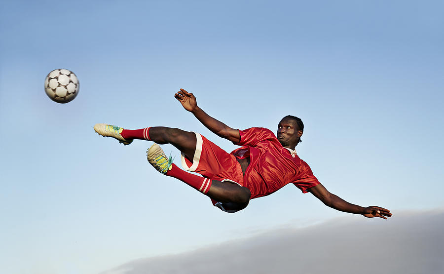 Football player about to kick ball in the air Photograph by Klaus Vedfelt