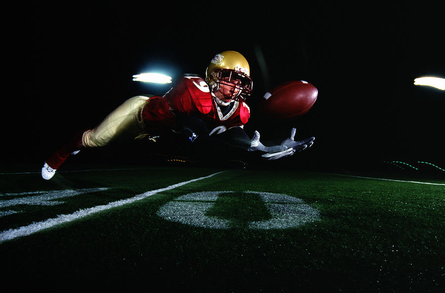 Football player diving to catch ball Photograph by John Giustina