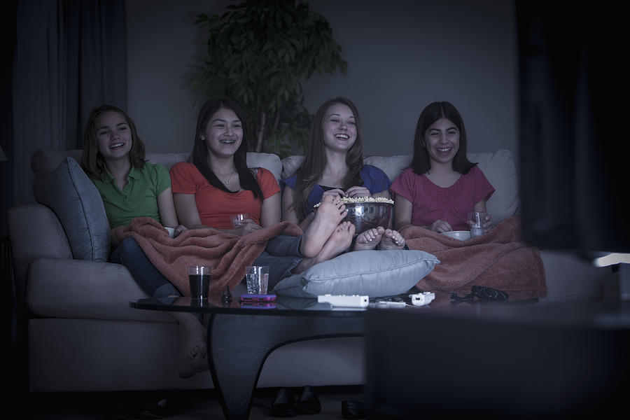 Friends eating popcorn and watching a movie Photograph by John Fedele