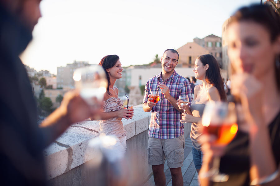 Friends having drinks on balcony Photograph by Cultura RM Exclusive/Antonio Saba