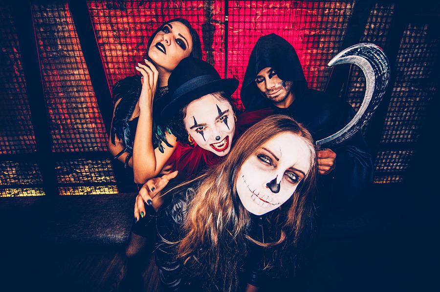 Friends in Halloween costumes taking photos in party photo booth Photograph by Wundervisuals