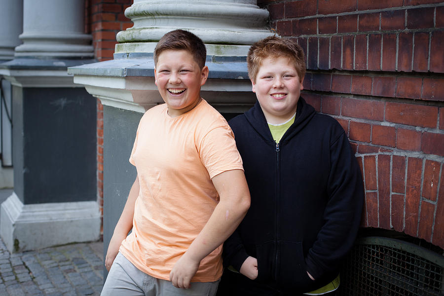 Friendship: Two Overweight Teenage Boys In Front Of Their School Photograph by Fotografixx