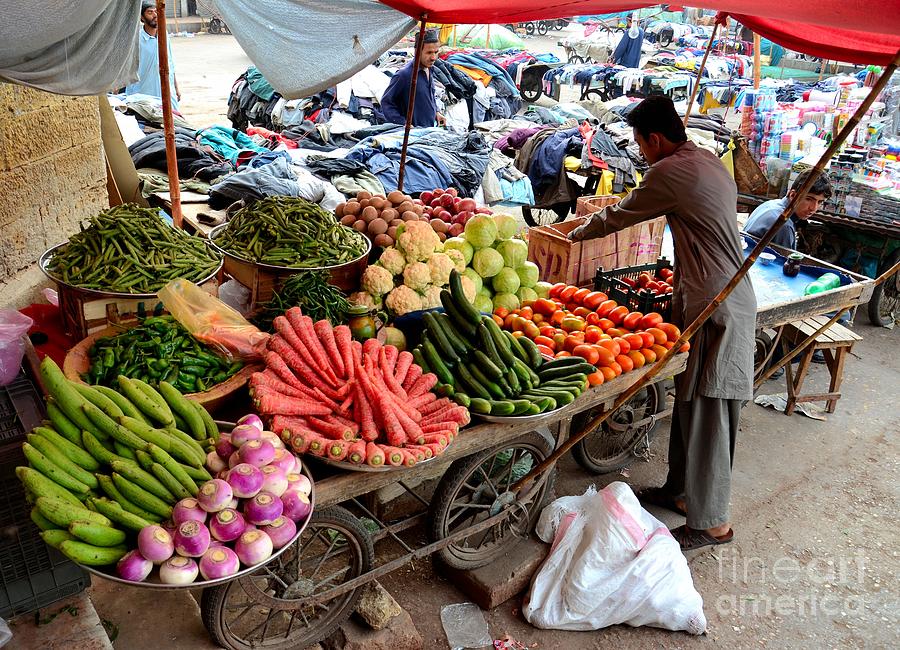 Fruit and vegetable seller tends to his cart outside Empress Market Karachi Pakistan Photograph by Imran Ahmed