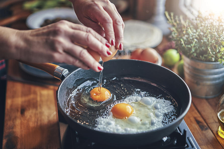Frying Egg in a Cooking Pan in Domestic Kitchen Photograph by GMVozd