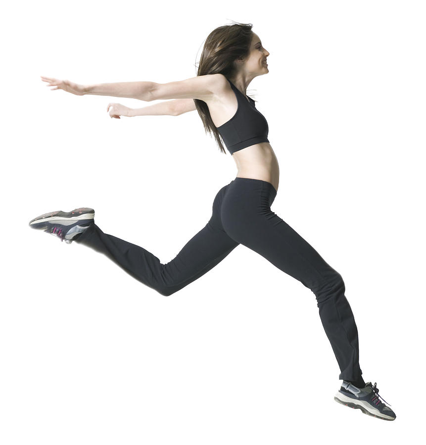 Full Body Shot Of A Young Adult Woman In A Workout Outfit As She Jumps Through The Air Photograph by Photodisc