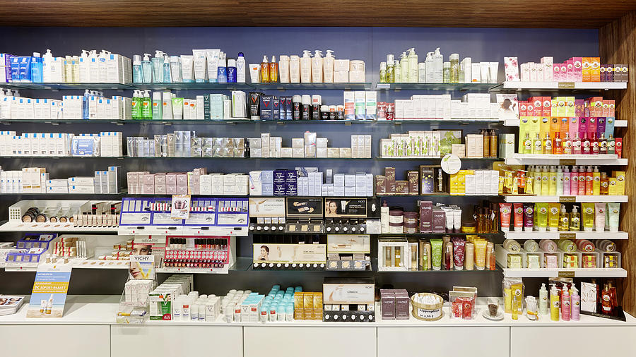 Full cosmetics shelves in a german pharmacy showing many products Photograph by Clu