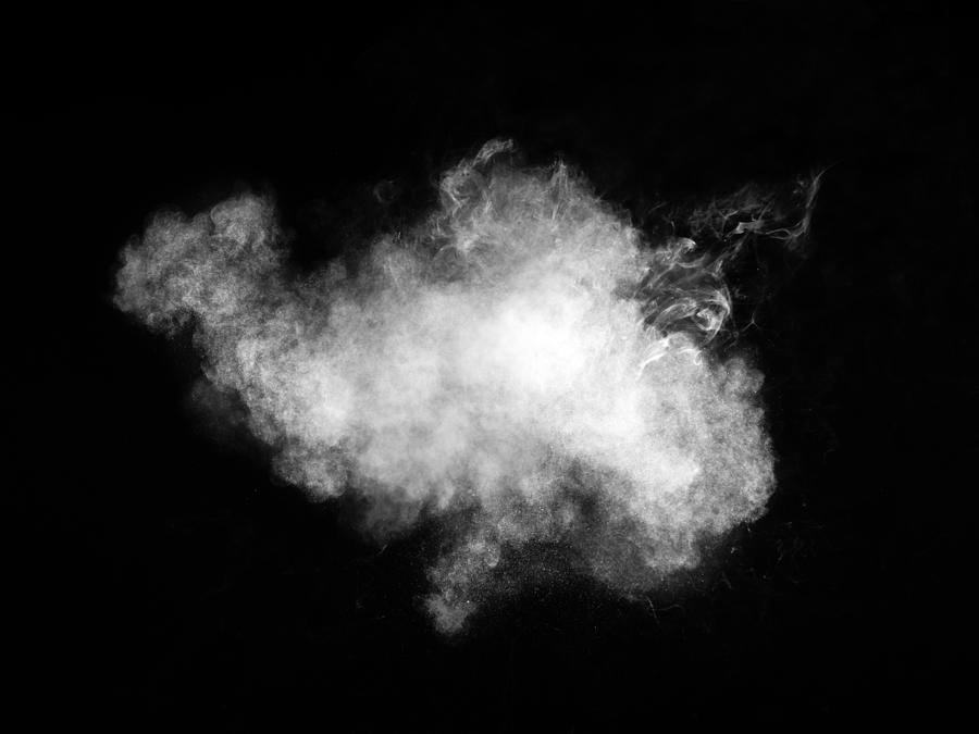 Full frame of forms and textures of an explosion of powder and smoke of color white and gray on a black background. Photograph by Jose A. Bernat Bacete