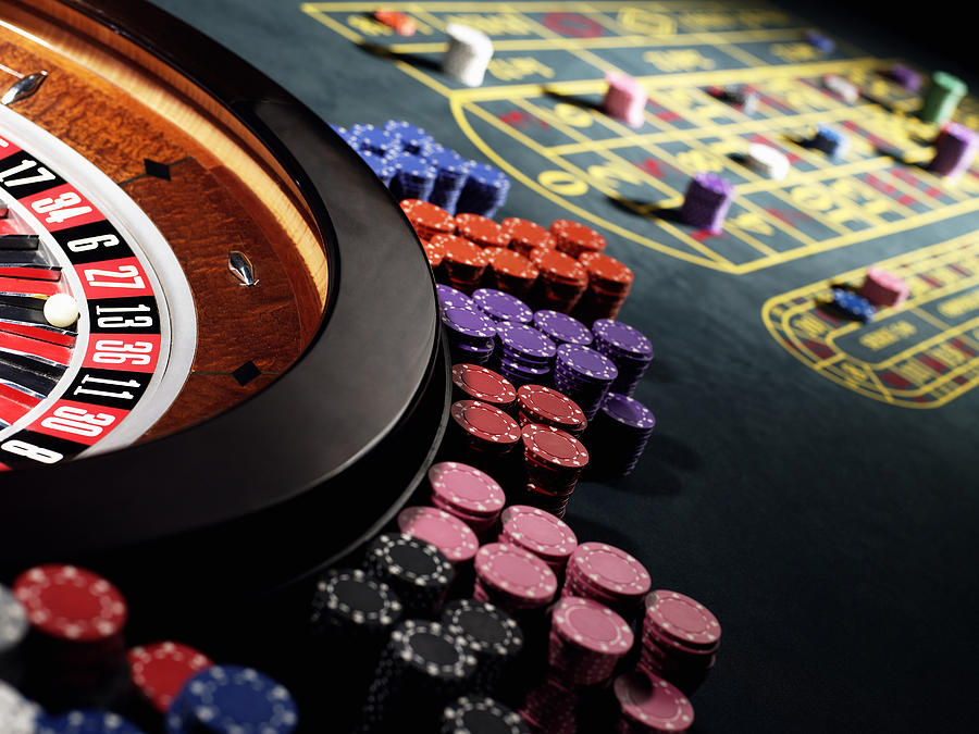 Gambling chips stacked around roulette wheel on gaming table Photograph by Michael Blann