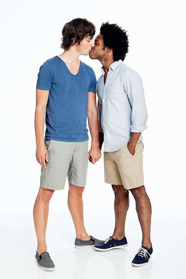 Gay couple kissing against white background Photograph by Image Source