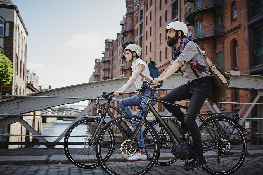 Germany, Hamburg, couple riding electric bicycles at Old Warehouse District Photograph by Westend61