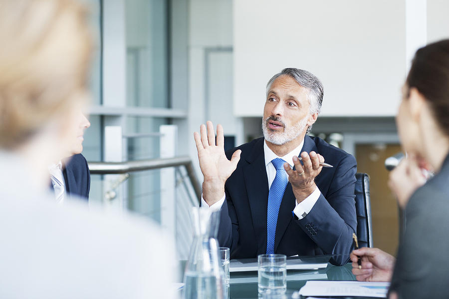 Gesturing businessman leading meeting in conference room Photograph by Martin Barraud