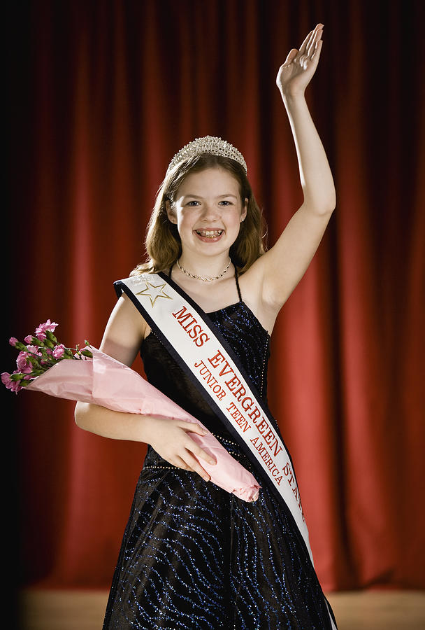 Girl (11-13) waving on stage with bouquet of flowers in beauty pageant Photograph by Andersen Ross