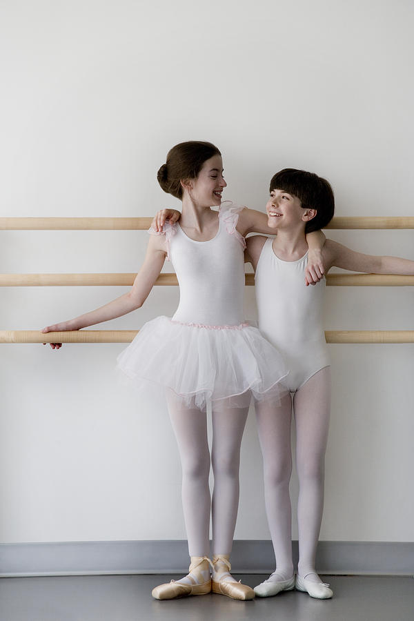 Girl and boy (12-14) standing together in ballet class, smiling Photograph by David Sacks