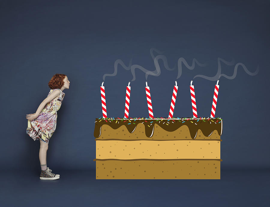 Girl blowing out candles on cartoon birthday cake Photograph by Flashpop