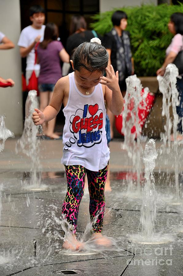 Girl child plays with water at fountain Singapore Photograph by Imran Ahmed