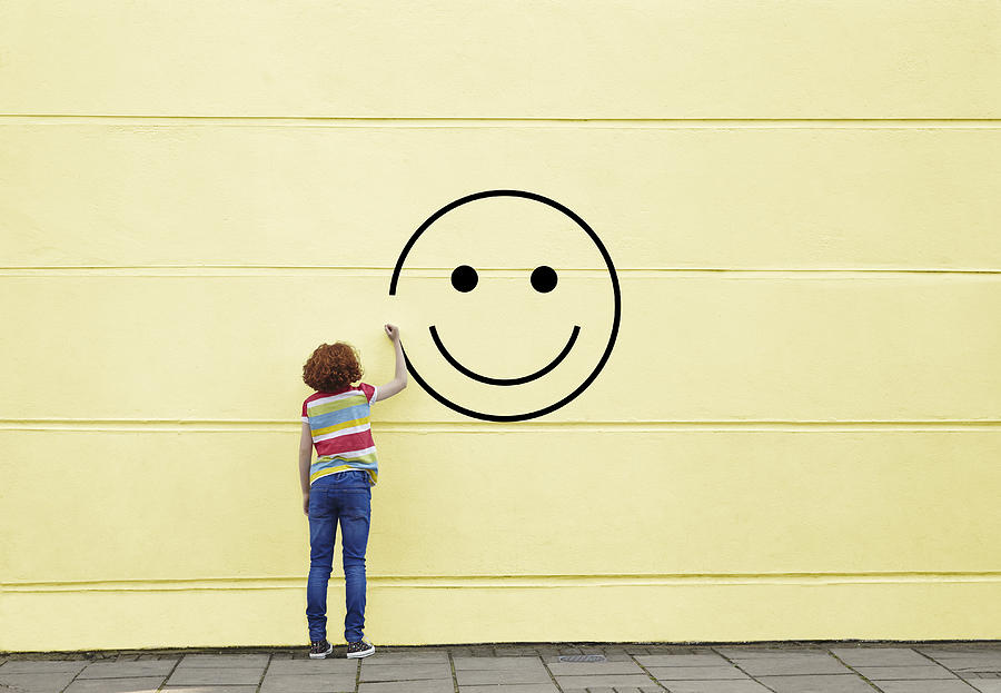 Girl drawing smiley face on to a wall Photograph by Flashpop