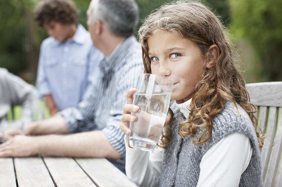 Girl drinking water at picnic table Photograph by Paul Bradbury