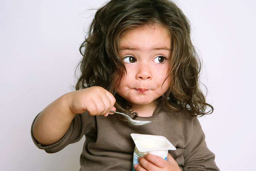 Girl Eating Yogurt Photograph by Weekend Images Inc.