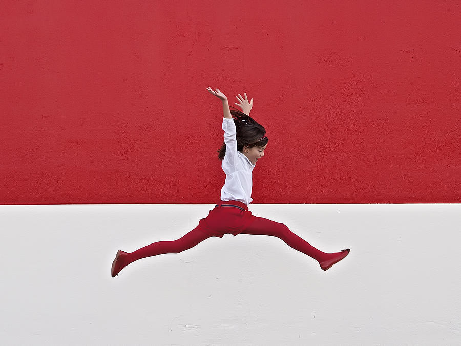Girl jumping in air at red wall Photograph by Santiago Bañón
