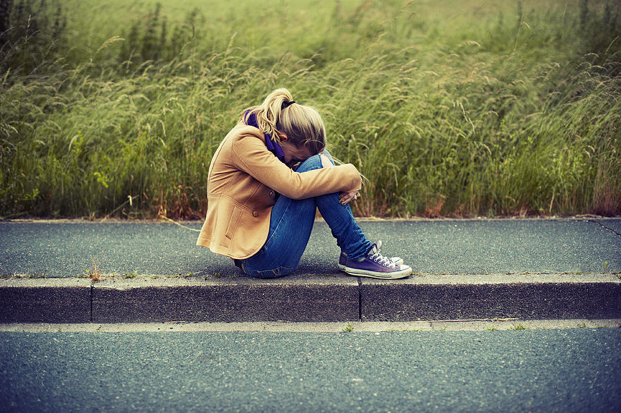 Girl sitting on sidewalk, hiding face Photograph by Elisabeth Schmitt