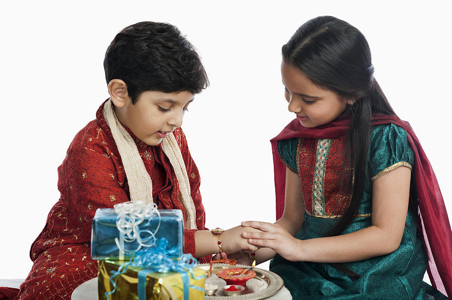 Girl tying rakhi on her brother wrist Photograph by Uniquely India
