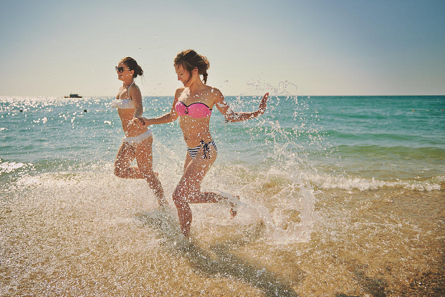 Girls running in the shallow water Photograph by Roman Makhmutov