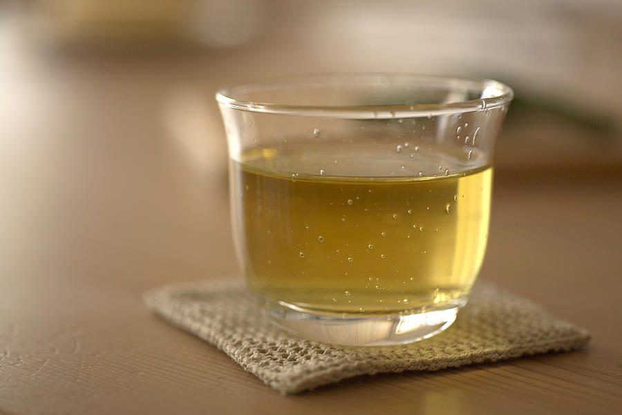 Glass of green tea on coaster, close-up Photograph by Ultra F