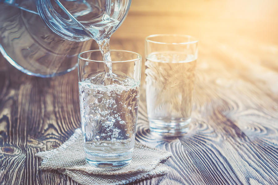 Glass of water on a wooden table Photograph by YSedova