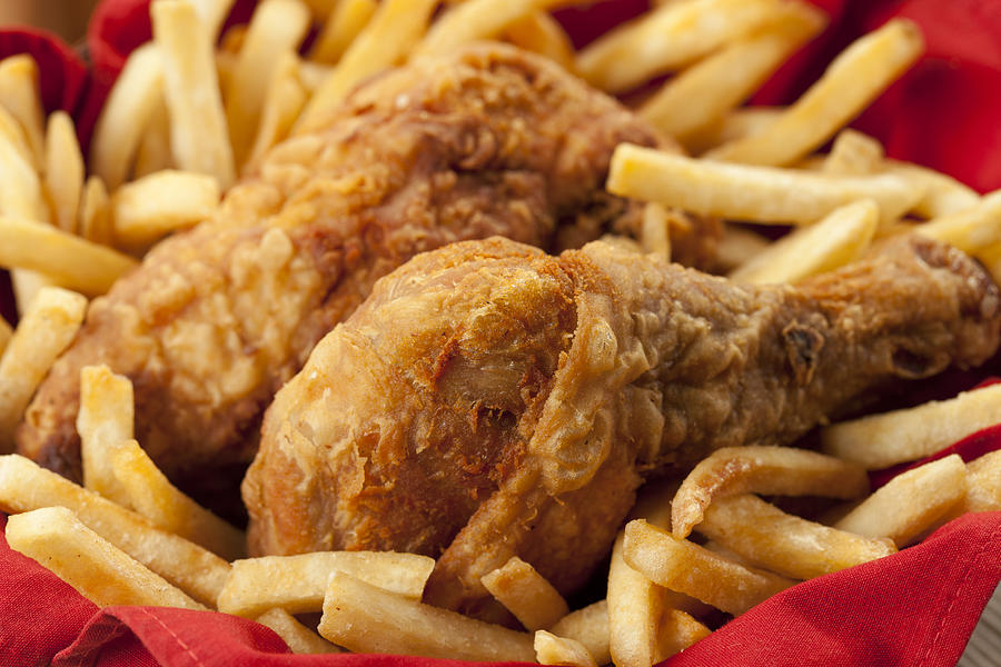 Golden fried chicken on a bed of French fries and red napkin Photograph by Aleaimage