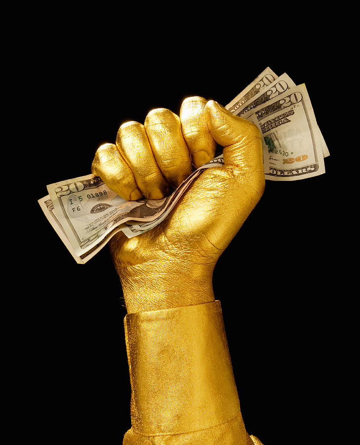 Golden hand clutching money Photograph by PM Images