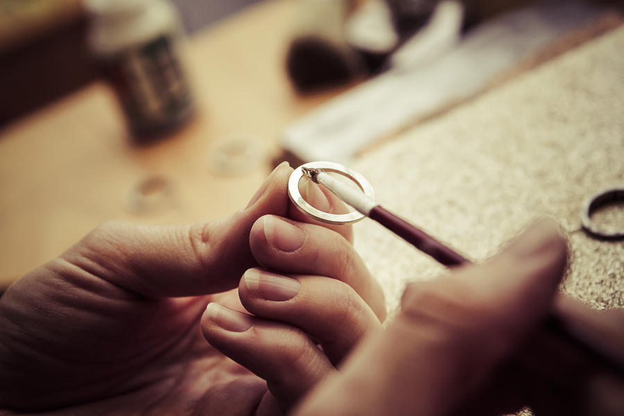 Goldsmith working on wedding rings, applying chemical on surface Photograph by Westend61