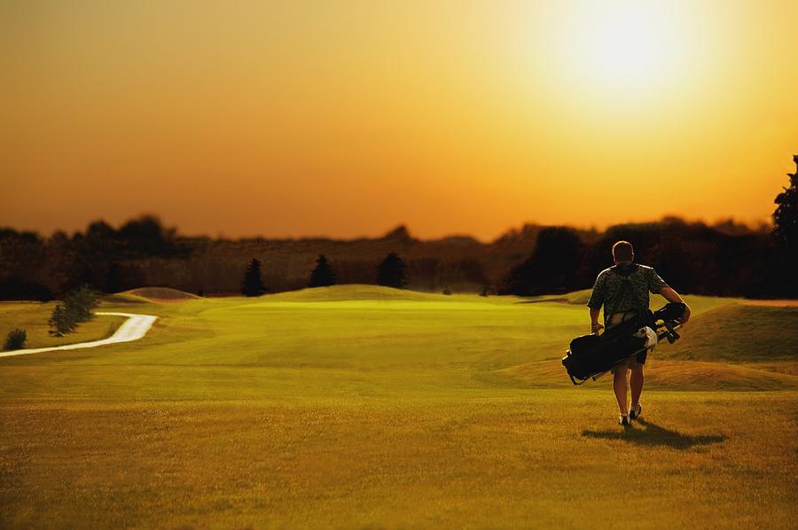 Sunset Photograph - Golfer Walking On A Golf Course by Darren Greenwood