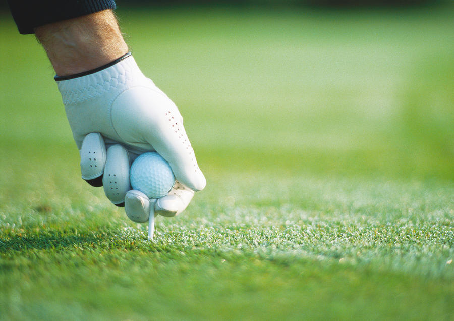 Golfers gloved hand teeing up, close-up Photograph by Laurence Mouton
