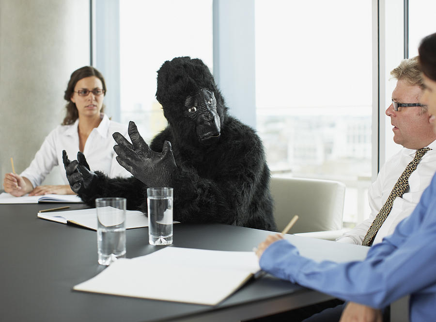 Gorilla and businesspeople having meeting in conference room Photograph by Paul Bradbury