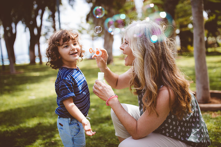 Grandma and grandson laughing and blowing bubbles at the park Photograph by Wundervisuals