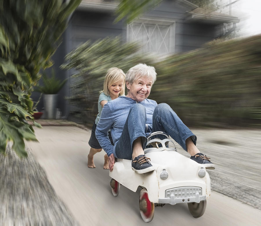 Grandson pushing grandmother on his toy car Photograph by Jlph