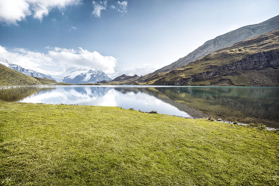 Grassy patch next to lake with mountain reflections Photograph by James ONeil