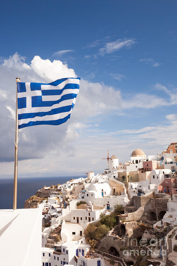 Greek Photograph - Greek flag waving on Oia - Santorini - Greece by Matteo Colombo