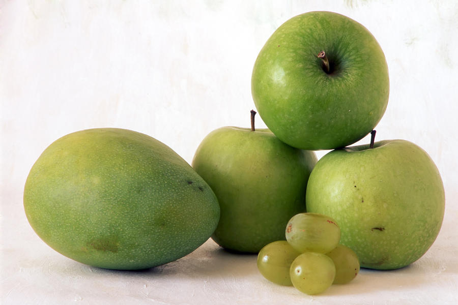 Green apple and mango on painted background Photograph by Sasas ...