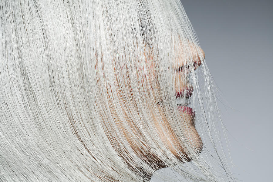 Grey haired woman profile with hair covering face. Photograph by Andreas Kuehn