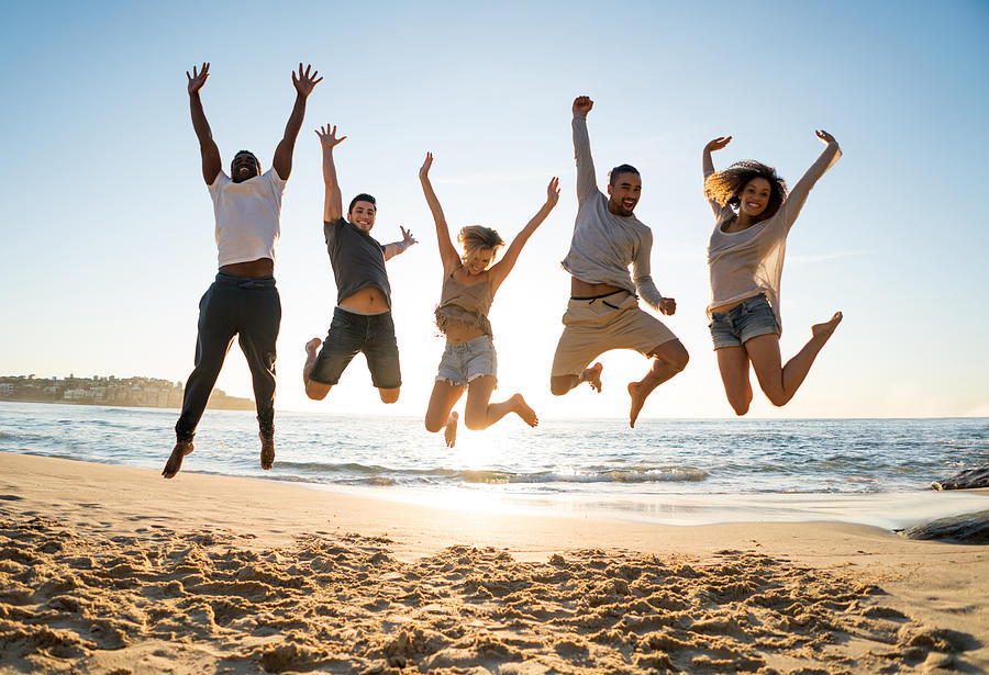 Group of friends jumping at the beach Photograph by Andresr