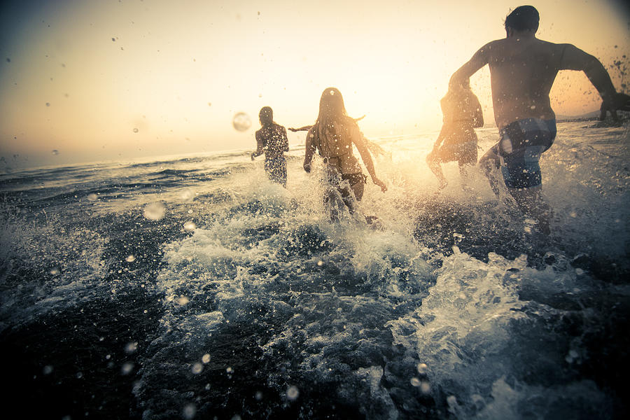 Group of friends running into the water Photograph by Mihailomilovanovic