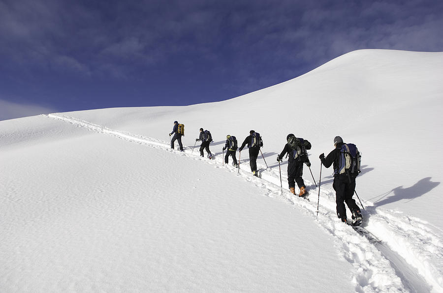Group of people climbing in snow, low angle view, rear view Photograph by Darryl Leniuk